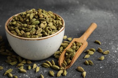 Siyah arka planda kakule baharatlı kase ve ahşap kepçe, yakın plan.