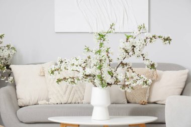 Aydınlık oturma odasındaki masada çiçekli bir vazo.