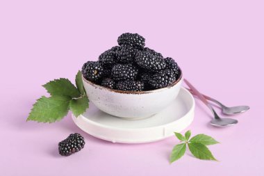 Leylak arkaplanda olgun böğürtlenlerle dolu bir kase.