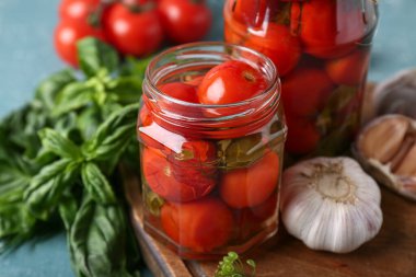 Fesleğen ve sarımsaklı konserve domatesler turkuaz grunge arka planda, yakın plan.