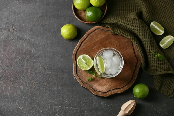 Bir bardak nane yaprağı ve siyah arka planda ahşap sıkacağı ile doldurulmuş limon suyu.