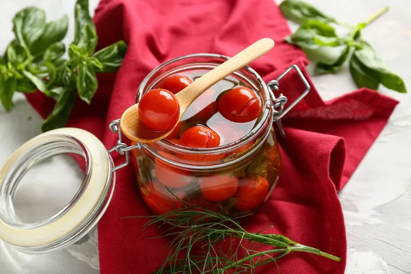 Fesleğenli konserve domates kavanozu ve beyaz grunge arka planda peçete, yakın plan.