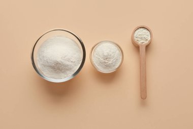 Bej arka planda ahşap kepçe ile pudralanmış süt kaseleri