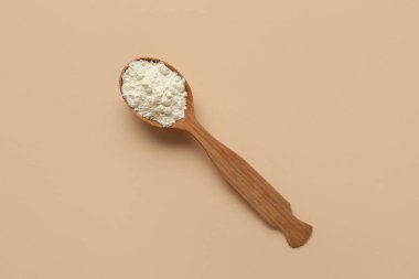 Bej arka planda pudra sütü olan tahta kaşık.