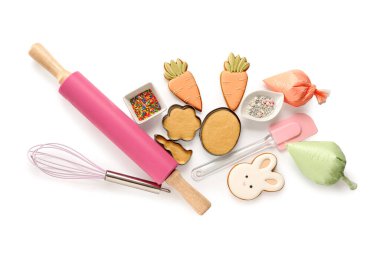 Paskalya kurabiyeli taze hamur, krema torbaları ve beyaz arka planda mutfak aletleri.