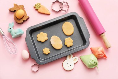 Paskalya kurabiyeli taze hamur, pipo torbaları, pembe arka planda yumurta ve mutfak aletleri.