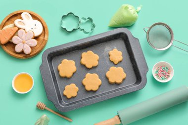 Ballı çiğ Paskalya kurabiyeleri, boru torbası ve turkuaz arka planda mutfak aletleri.