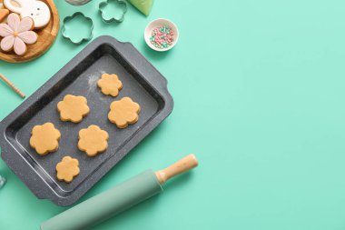 Turkuaz arka planda mutfak aletleri olan çiğ Paskalya kurabiyeleri.