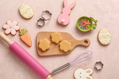 Pembe arka planda mutfak aletleri olan çiğ Paskalya kurabiyeleri.
