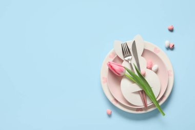 Kağıt tavşanlı Paskalya masası, mavi arka planda yumurta ve lale çiçeği.