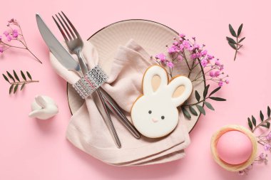 Tavşan, yumurta, zeytin dalları ve pembe arka planda çingene çiçekleri şeklinde kurabiyeler.