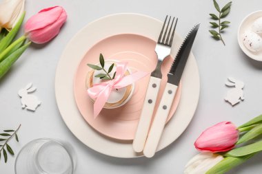 Paskalya sofrasında yumurta, lale çiçeği ve gri arka planda zeytin dalları var.