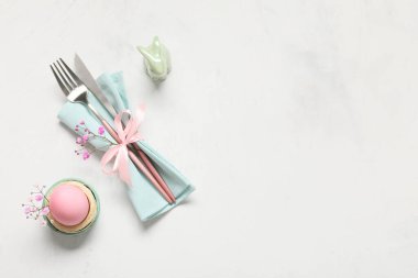 Beyaz arka planda boyanmış yumurta, çingene çiçekleri ve seramik tavşanlı Paskalya masası.