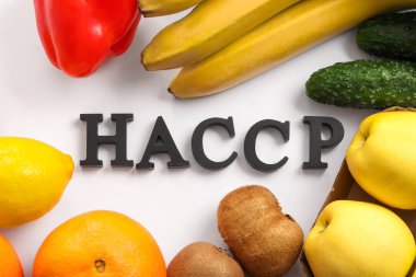 HAZARD ANALYSIS 'in kısaltılmışı ve beyaz arka planda taze meyve ve sebzelerin yer aldığı CİNAYET noktalarının