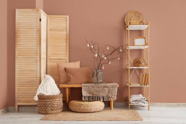 Ağaç dallı vazo ve odada kahverengi duvarın yanındaki bankta Paskalya yumurtası.