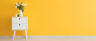 Vazo dolusu lale çiçeği, Paskalya yumurtası ve sarı duvarın yanındaki masada bir piliç. Tasarım için pankart