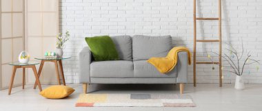 Gri kanepe ve boyalı yumurtalarla aydınlık oturma odasının içinde. Paskalya kutlaması