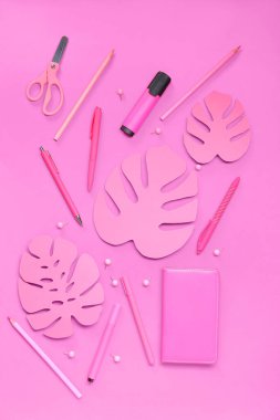 Pembe arka planda farklı kırtasiye malzemesi ve kağıt palmiye yaprakları olan kompozisyon