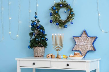 Oturma odasında köknar ağacı ve geleneksel Hanuka süslemeleri olan beyaz masa.