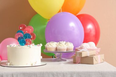 Doğum günü partisi için içinde pasta, şeker ve balon olan bir masa.