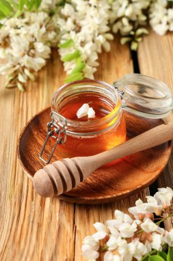 Akasya çiçekli tatlı bal kavanozu ve ahşap zemin üzerinde dipper.
