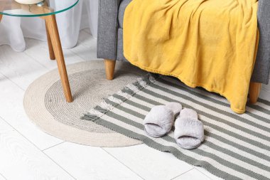 Oturma odasındaki halıda gri terlikler, yakın plan.