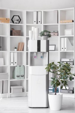 Ofisinde kağıt bardak ve bitkiler olan modern su soğutucusu.