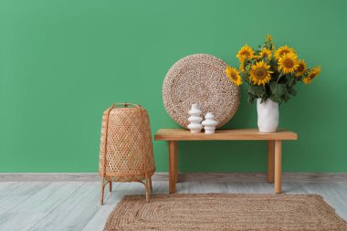 Hasır lambalı şık bir oda ve yeşil duvarın yanında bir vazo ayçiçeği buketi