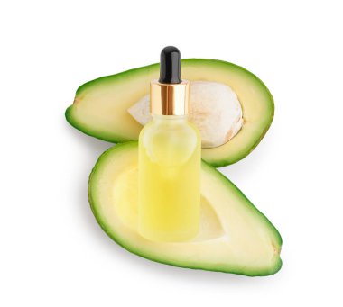 Bir şişe temel yağ ve beyaz arka planda taze avokado.