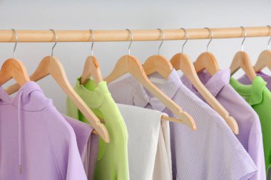 Ahşap askılar, şık kadın kıyafetleri, ışık duvarı yakınında, yakın plan.