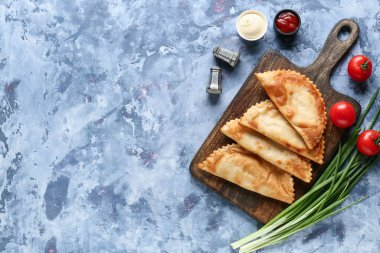 Lezzetli cheburekler, taze sebzeler ve soslar mavi grunge masasında.