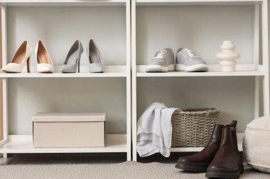 Koridordaki ışıklı duvarın yanında kadın ayakkabıları olan raflar.