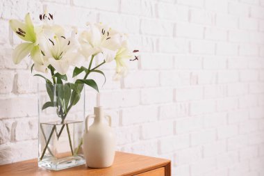 Beyaz tuğla duvarın yanındaki masada güzel çiçekli vazo, yakın plan.