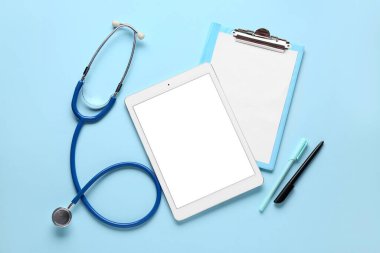 Tablet bilgisayar, steteskop ve klasör mavi arkaplan üzerinde boş kağıt levha