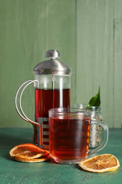 Çaydanlıklı kompozisyon ve yeşil grunge masasında bir kupa siyah çay.