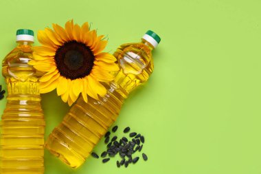Ayçiçekli yağ şişeleri ve yeşil arka planda tohumlar