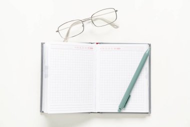 Beyaz arkaplanda boş defter, gözlük ve kalem ile kompozisyon