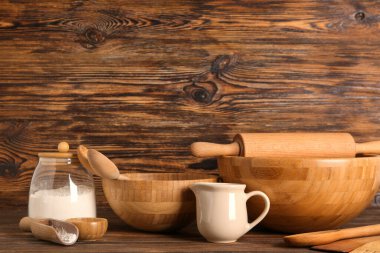 Kahverengi ahşap arka planda farklı mutfak aletleri ve malzemeler, yakın plan.