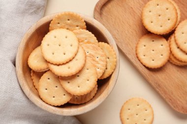 Ahşap kase ve kesme tahtası bej arka planda lezzetli krakerler, yakın plan