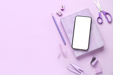 Leylak arka planında okul kırtasiyesi ve cep telefonu ile kompozisyon