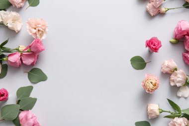 Güzel pembe Eustoma çiçeklerinden yapılmış çerçeve ve beyaz arkaplanda yapraklar