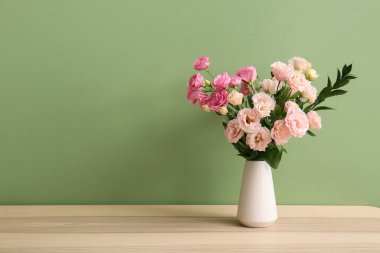 Oturma odasındaki ahşap masada güzel Eustoma çiçekleri olan vazo, yakın plan.