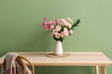 Oturma odasındaki ahşap masada güzel Eustoma çiçekleri olan vazo.