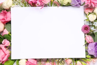 Beyaz zemin üzerinde boş kağıt sayfa ve farklı çiçekler olan kompozisyon, yakın plan