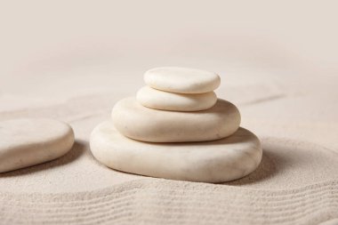 Arka plan olarak kumdaki kaplıca taşları ve çizgilerden oluşan bir kompozisyon, yakın plan. Zen kavramı