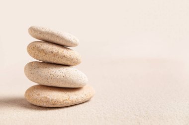 Arka plan olarak açık kumlar üzerinde spa taşı yığını olan kompozisyon, yakın plan. Zen kavramı