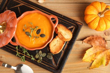 Tahta arka planda çekirdekli, kıtır kıtır ve kekik soslu lezzetli balkabağı kremalı çorba.