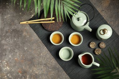 Çaydanlık, fincanlar ve siyah grunge arka planda tropikal yapraklarla çay seremonisi için ayarlandı.