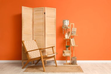 Hasır koltuklu, raflı ve turuncu duvarlı oturma odasının içinde.