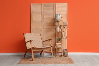 Hasır koltuklu, raflı ve turuncu duvarlı oturma odasının içinde.